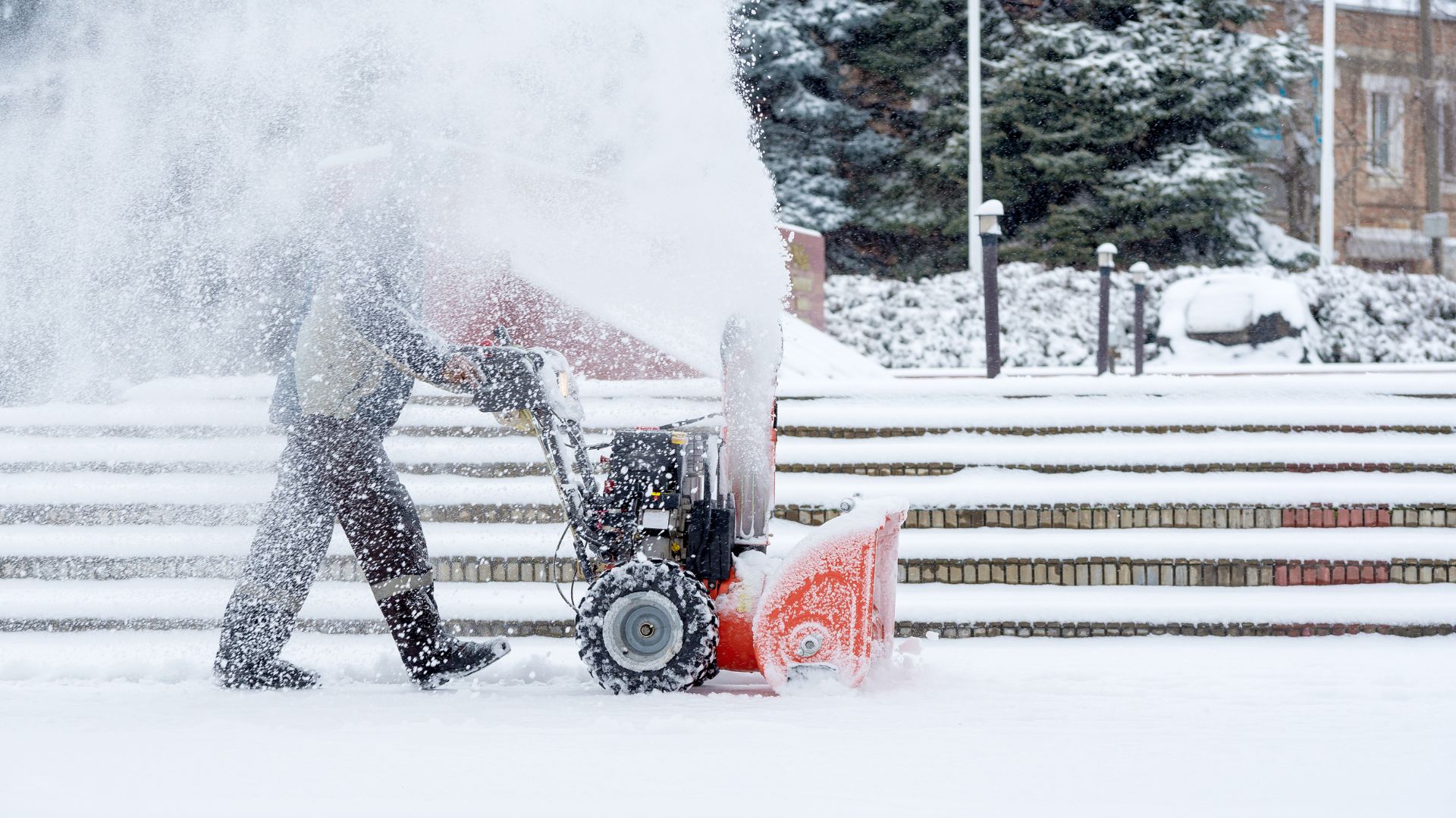 person using a snow blower in a parking lot